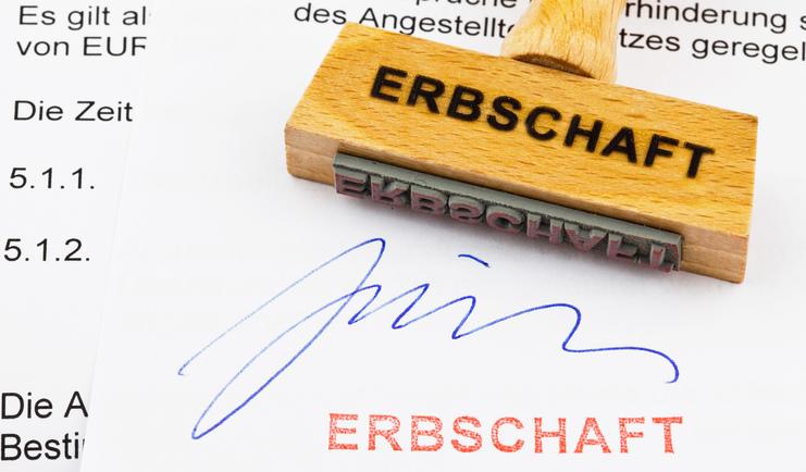Holzstempel mit Aufschrift "ERBSCHAFT" auf einem Dokument, das eine Unterschrift und den Stempelabdruck zeigt.